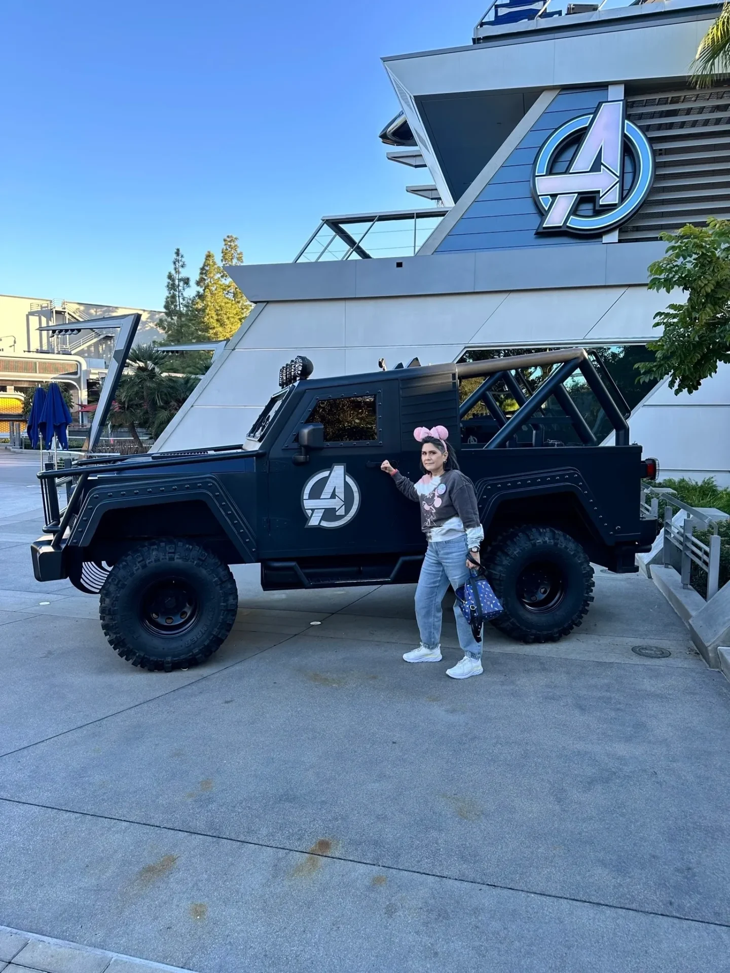 A girl standing next to an suv parked in front of a building.