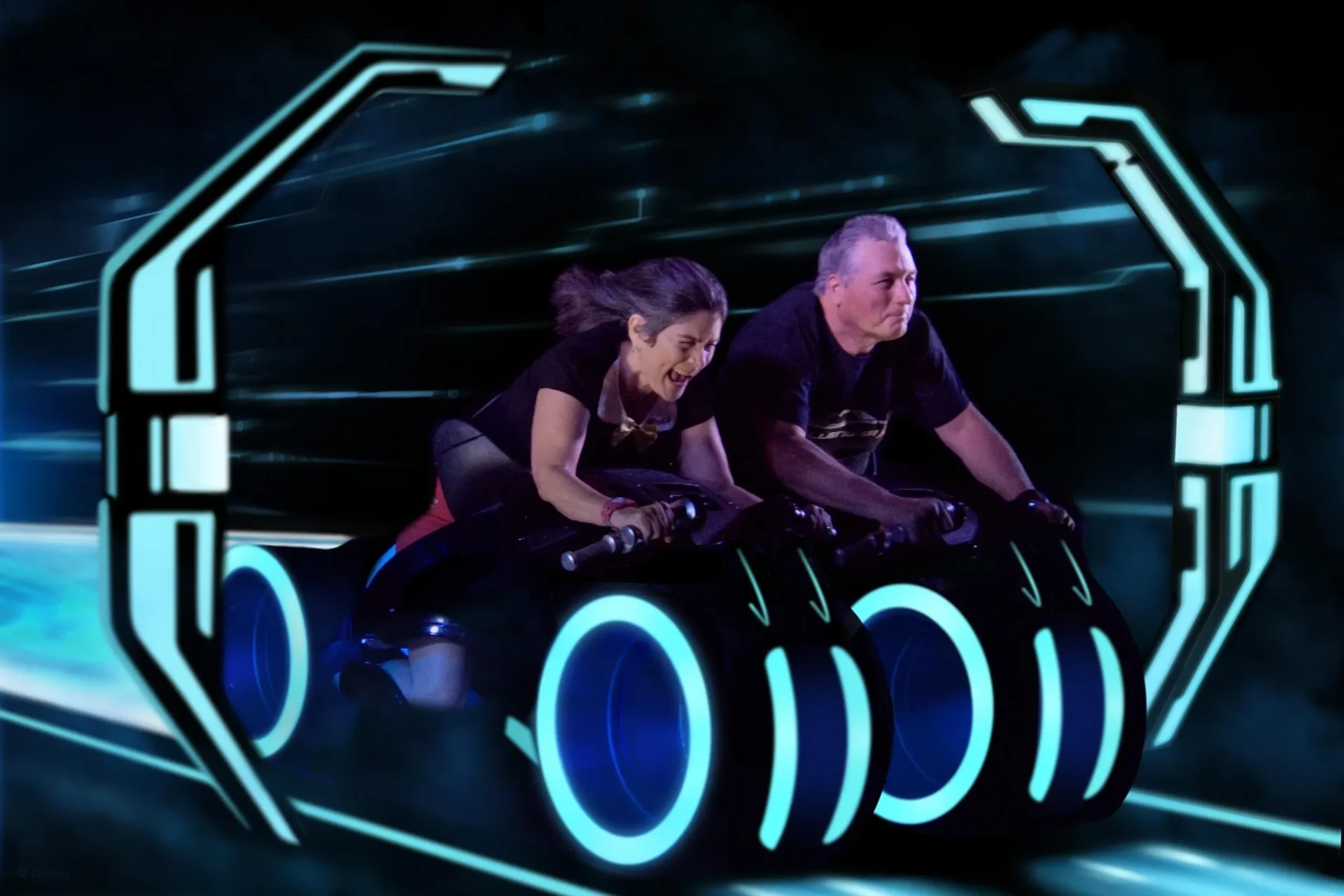 A man and woman riding on the tron coaster.