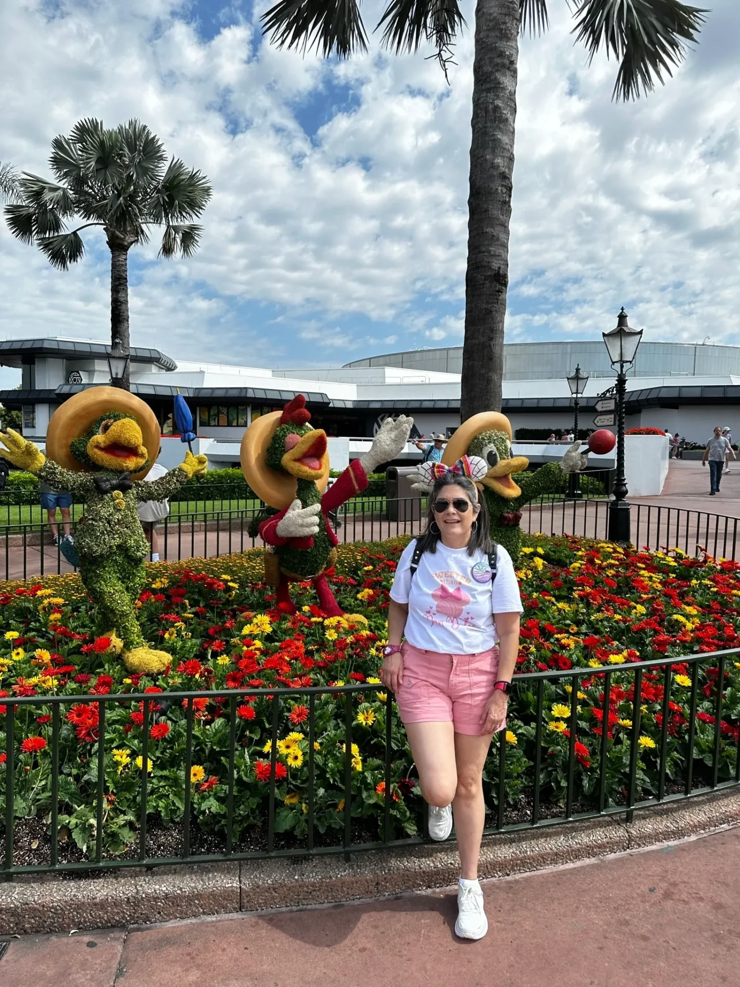 A woman standing in front of flowers and trees.