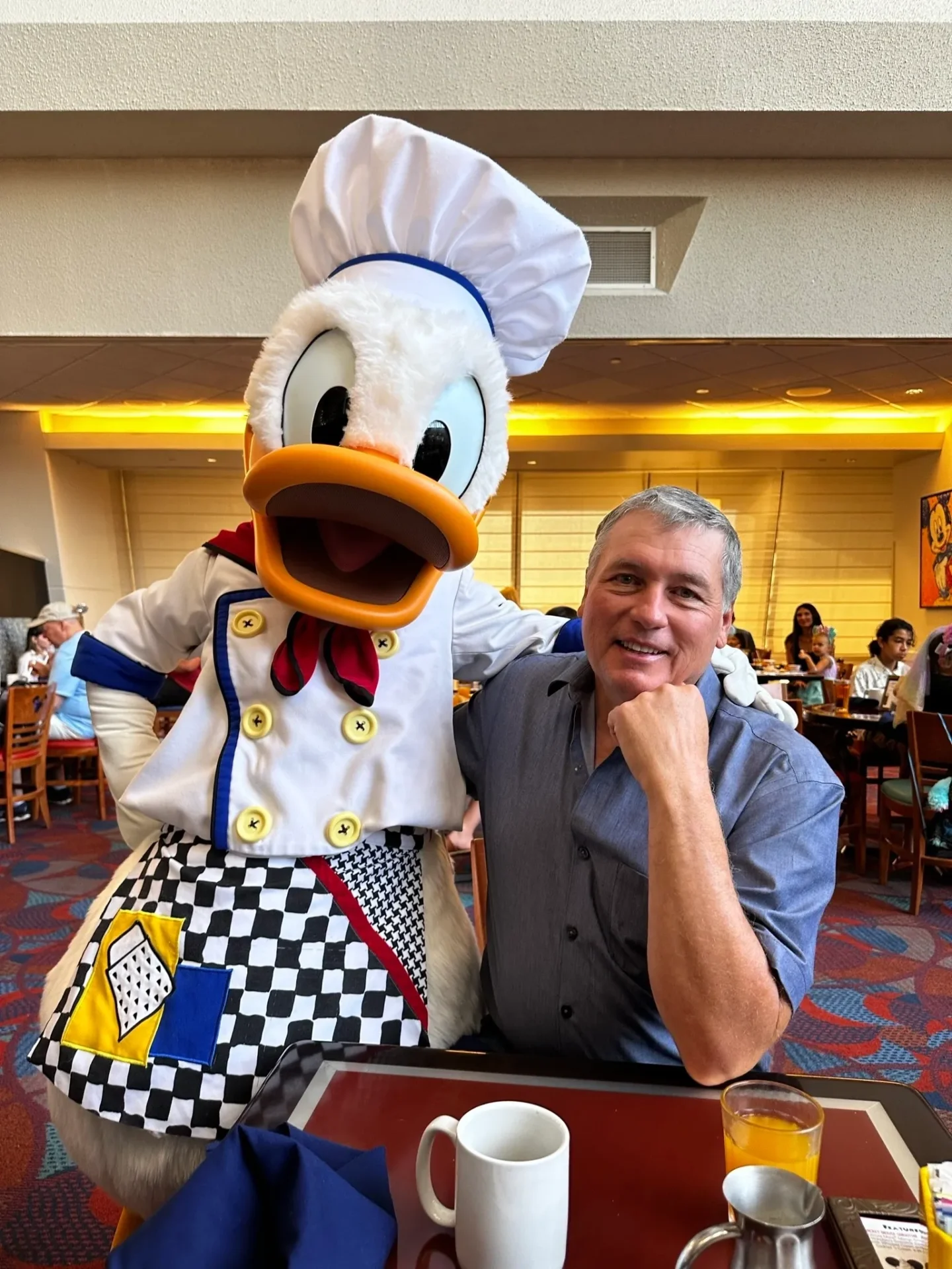 A man posing with a chef duck at a restaurant.