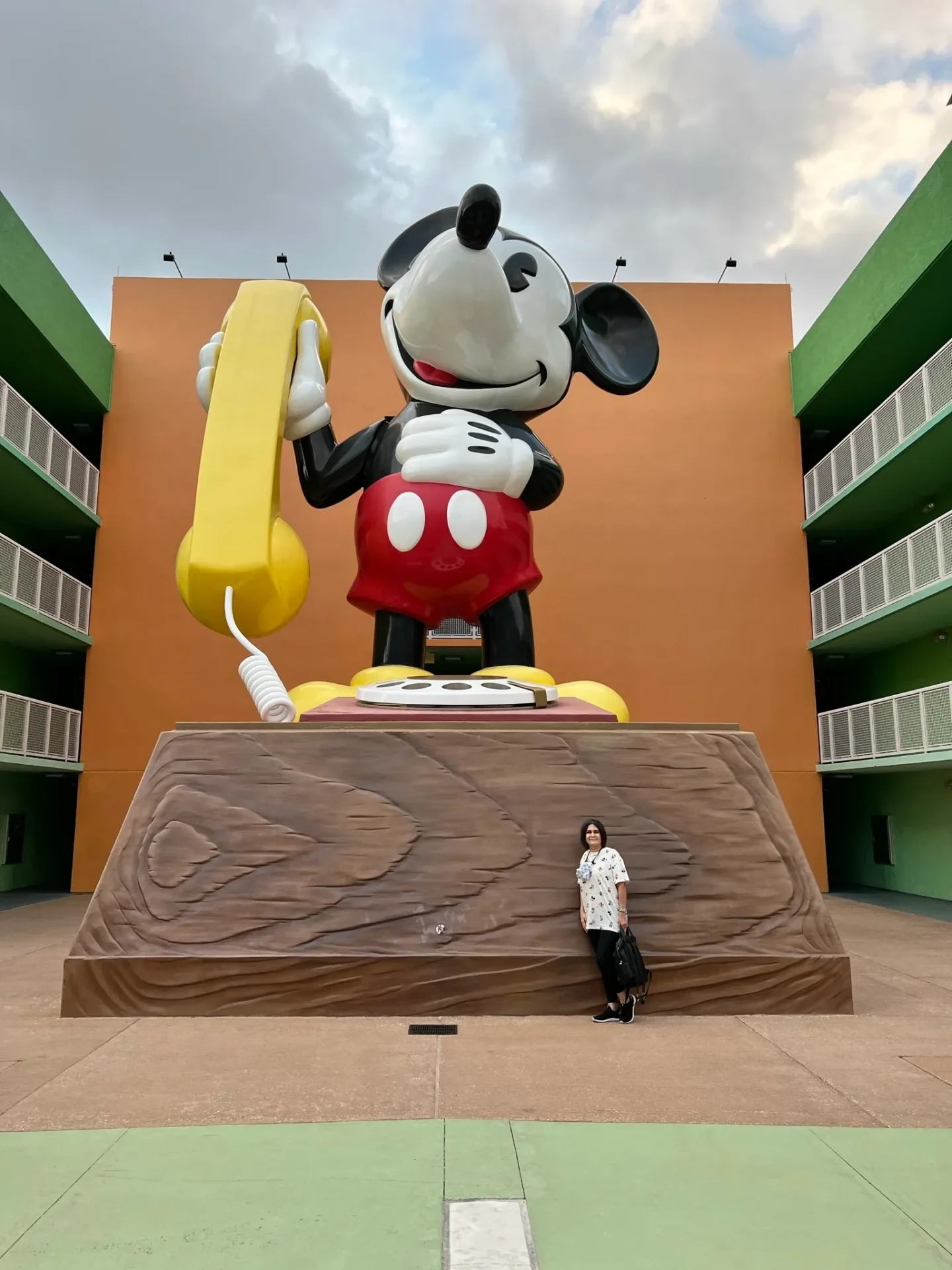 A woman standing next to a large mickey mouse statue.