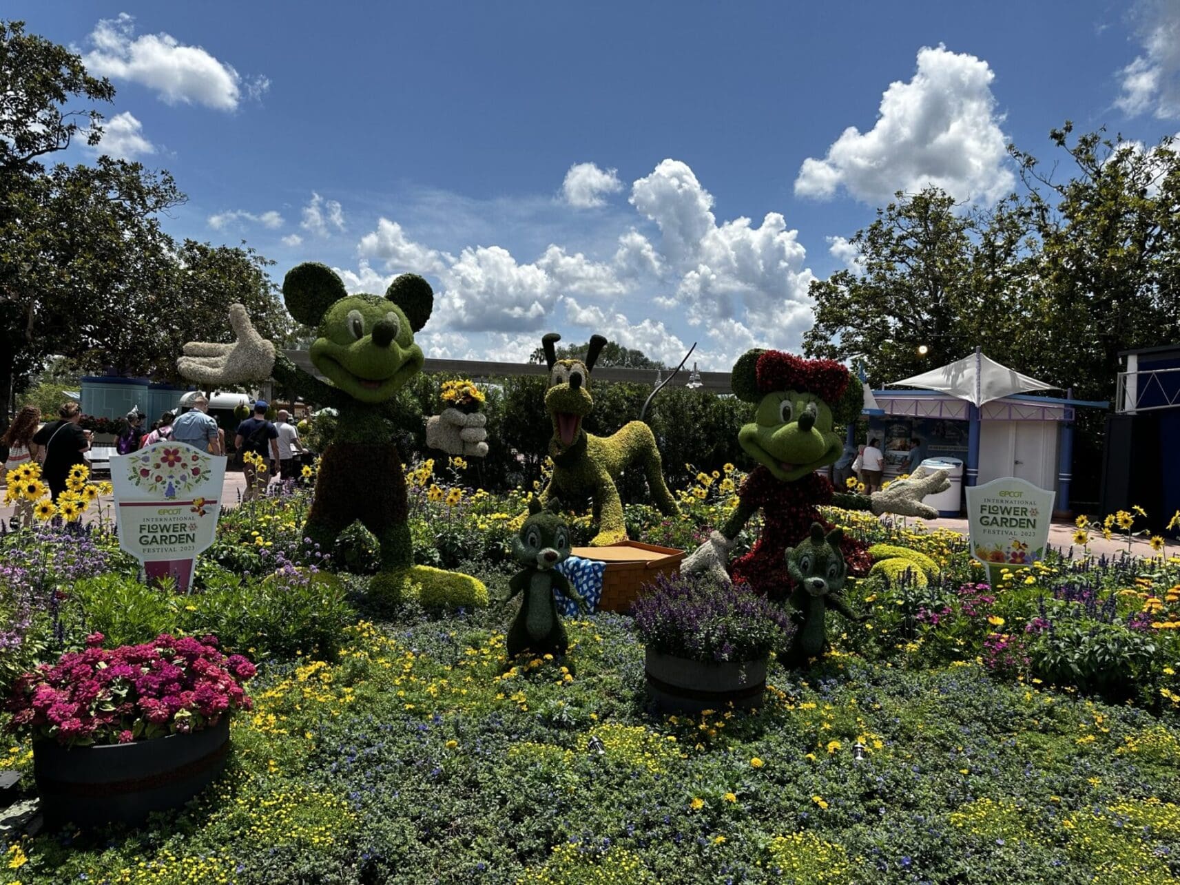 A group of mickey mouse statues in the middle of a garden.